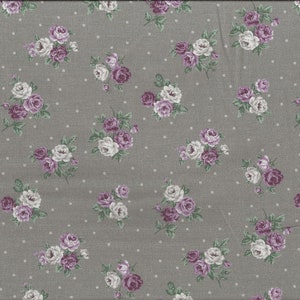 Può includere: Tessuto grigio con un motivo ripetuto di pois bianchi e bouquet di rose viola e bianche. Il tessuto ha un aspetto strutturato e un righello giallo è visibile lungo il bordo destro.