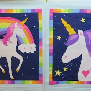 Puede incluir: Dos paneles de tela con un fondo azul oscuro que presentan unicornios blancos con acentos de arcoíris y estrellas. El unicornio del panel izquierdo está de pie debajo de un arcoíris y el unicornio del panel derecho tiene una melena morada y está rodeado de estrellas.