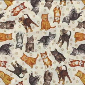 Op de afbeelding: Een beige stof met een herhalend patroon van kleurrijke katten. De katten zijn in verschillende poses en kleuren, waaronder oranje, grijs, bruin en zwart. De achtergrond is lichtbeige met een subtiel pootprintpatroon.