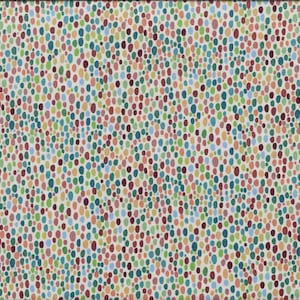 May include: Fabric with a repeating pattern of colorful, oval-shaped dots in shades of red, green, blue, yellow, and brown. A yellow ruler with black markings is visible on the right side, measuring in inches.
