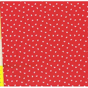 Peut inclure: Tissu rouge avec un motif de cœurs blancs. Le tissu est mesuré avec une règle en pouces.