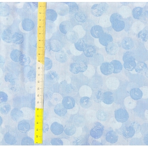 Könnte beinhalten: Ein hellblauer Stoff mit einem weißen und hellblauen Tupfenmuster. Der Stoff ist strukturiert und hat einen dezenten Glanz.
