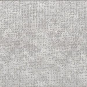 Op de afbeelding: Een close-up van een grijze, textuurrijke stof met een subtiel patroon van kleine witte stippen. Een gele liniaal is zichtbaar aan de rechterkant van de afbeelding.