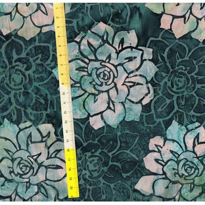 Pode incluir: Tecido azul-petróleo com um padrão floral branco. O tecido apresenta um padrão repetitivo de grandes flores estilizadas com um centro rosa claro.