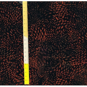 Pode incluir: Tecido preto com um padrão abstrato vermelho e marrom. O tecido é medido com uma régua que mostra 20 polegadas.