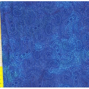 Op de afbeelding: Blauwe paisley stof met een textuur. De stof heeft een herhalend patroon van paisley vormen in een lichtere blauwe tint.
