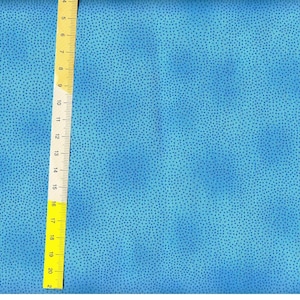 May include: A close-up of a blue fabric with a subtle, speckled pattern. The fabric is textured and has a slightly iridescent sheen.
