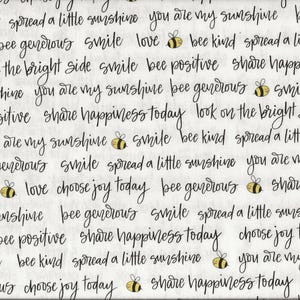 Könnte beinhalten: Weißer Stoff mit schwarzem Schreibschrifttext und gelben Bienen. Sätze wie "spread a little sunshine", "you are my sunshine" und "bee generous". Ein gelbes Lineal befindet sich auf der linken Seite, gemessen in Zentimetern.