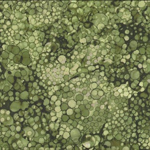 May include: Green fabric with a pattern of overlapping circles in shades of green and white. A yellow ruler with black markings is on the right side of the fabric, showing measurements in inches.