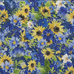 Puede incluir: Una tela azul con un patrón floral con girasoles amarillos y flores azules. La tela tiene un efecto acuarela.