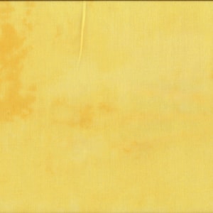 Könnte beinhalten: Ein gelber Stoff mit einer dezenten Textur und einigen hellbraunen Flecken. Der Stoff wird mit einem gelben Lineal gezeigt.