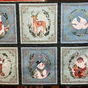 Op de afbeelding: Een kerststofpaneel met zes vierkanten met verschillende winterse taferelen. Elk vierkant heeft een blauwe achtergrond met een groene krans en een ander beeld erin, waaronder een ijsbeer, een hert, een duif, een kous, een sneeuwpop en de kerstman.