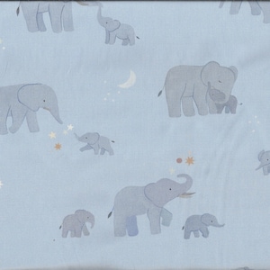 Könnte beinhalten: Hellblauer Stoff mit einem sich wiederholenden Muster aus grauen Elefanten, Sternen und Monden. Die Elefanten sind unterschiedlich groß, einige mit Baby-Elefanten. Das Design beinhaltet goldene und braune Sternakzente.