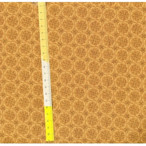 May include: A brown fabric with a repeating pattern of small, intricate, light brown snowflakes. A yellow ruler is visible on the right side of the image.