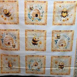 Könnte beinhalten: Weißes Stoffpaneel mit neun quadratischen Designs. Jedes Quadrat zeigt Aquarellillustrationen von Bienen, Bienenstöcken und Blumen, umrahmt von gelben und braunen Rändern. Der Stoff hat einen dekorativen Rand mit Bienen und gelben Streifen.