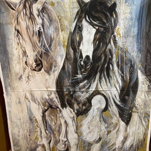 Può includere: Un pannello in tessuto artistico con due cavalli. Uno è principalmente bianco, l'altro nero e bianco. Lo sfondo presenta un design astratto con accenti dorati e blu. L'opera d'arte ha uno stile pittorico.