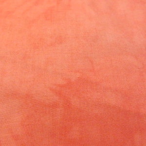 Puede incluir: Primer plano de una tela lisa de color coral con una textura sutil y desigual.