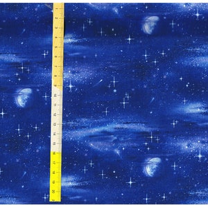 Könnte beinhalten: Ein blauer Stoff mit einem sich wiederholenden Muster aus weißen Sternen, Monden und Sternschnuppen. Der Stoff ist strukturiert und hat einen Aquarell-Effekt.