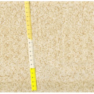 Pode incluir: Um close-up de um tecido bege com um padrão sutilmente salpicado. Uma régua amarela é colocada verticalmente no lado direito da imagem, com marcas de 1 a 20.