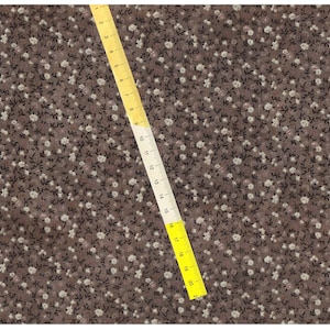 May include: Brown fabric with a white floral pattern. A yellow measuring tape is placed diagonally across the fabric.