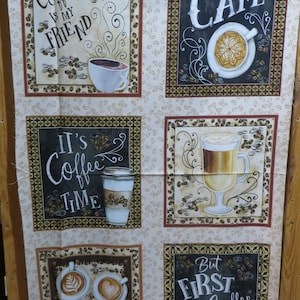 Op de afbeelding: Een beige stof met een koffiemotief. De stof heeft vier vierkanten met zwarte schoolbord-achtige borden waarop staat "Coffee is my friend", "Cafe", "It's Coffee Time" en "But First Coffee". Elk vierkant heeft een koffiekopje of mok met koffiebonen en swirls eromheen.