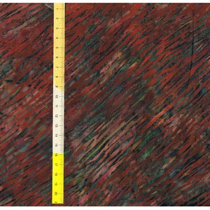 Pode incluir: Vista de perto de tecido com um padrão diagonal em tons de vermelho, verde e preto. Uma régua amarela é colocada verticalmente, mostrando medidas até 50 cm.