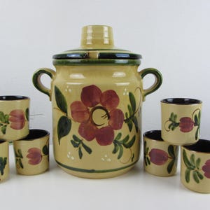 Può includere: Una brocca in ceramica vintage e sei tazze abbinate. La brocca è beige con un grande motivo floreale rosso e accenti verdi. Le tazze e la brocca hanno un interno nero. Un affascinante set floreale per servire bevande.