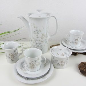 May include: A white porcelain tea set with a floral design. The set includes a teapot, creamer, sugar bowl, and two cups and saucers.