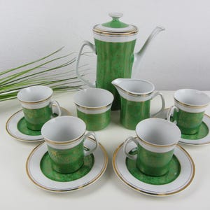 Può includere: Un set da tè verde e oro con una teiera, un creamer e sei tazze e piattini.