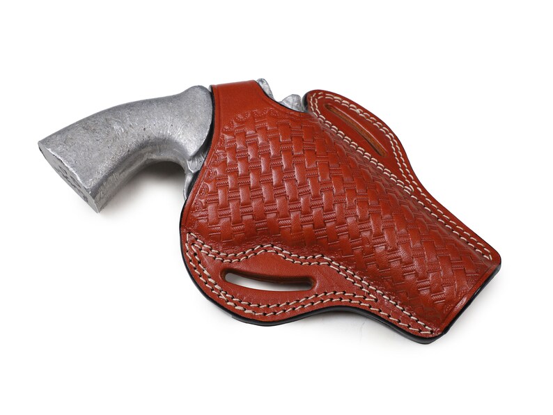 May include: A brown leather holster with a woven pattern and white stitching. The holster is designed to hold a handgun.