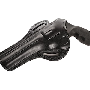 Può includere: Un fodero in pelle nera per un revolver. Il fodero ha un design cucito e un'apertura per la guardia del grilletto.