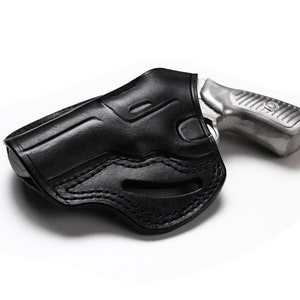 Puede incluir: Una funda de cuero negra para una peque&ntilde;a pistola plateada.