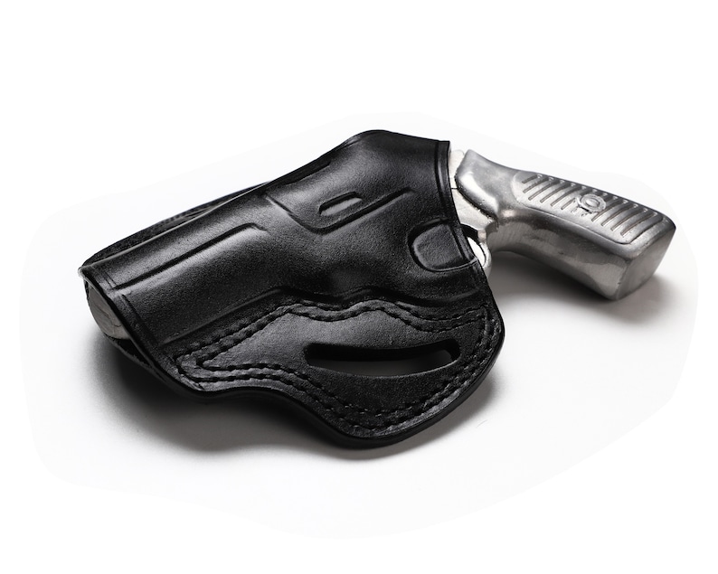 Puede incluir: Una funda de cuero negra para una peque&ntilde;a pistola plateada.