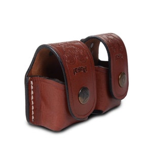 May include: Two brown leather shell holders with a snap closure. The holders are stitched with white thread and have a embossed design.