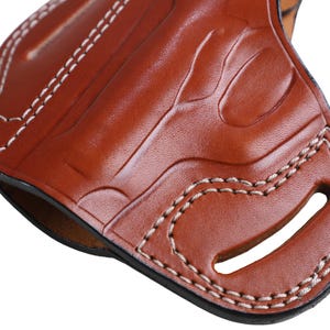 Handmade brown Left Hand leather OWB pancake holster by Pusat Holster, precision-molded for Beretta 84, 84BB, 84F, and 84FS Cheetah .380 ACP models. The image highlights the 100% premium genuine leather texture, hand-polished edges, and heavy-duty stitching on a white background. Features a secure thumb break with durable brass snaps and 304 stainless steel hardware. Designed for a perfect, rattle-free fit, offering a blend of classic style and tactical durability for daily carry.