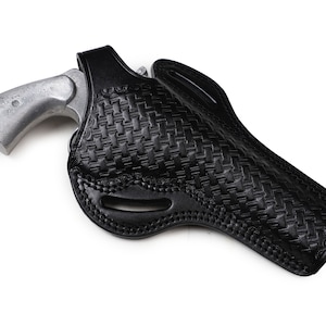 May include: Black leather holster with a woven basketweave pattern, holding a silver-colored revolver. The holster has a molded design and a belt loop. The revolver's grip is visible.