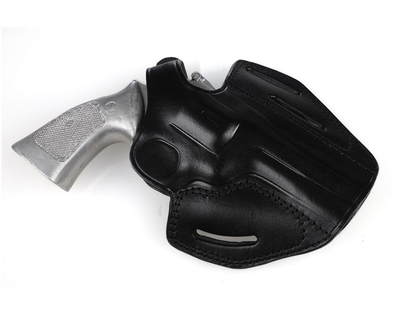 May include: A black leather holster with a silver revolver. The holster is molded to the shape of the gun and features stitching and a belt loop. The revolver has a textured grip.