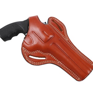 Könnte beinhalten: Ein braunes Lederholster mit einer schwarzen Pistole darin. Das Holster hat ein Ausschnittdesign und ist mit weißem Garn vernäht.