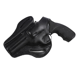 May include: A black leather holster with a black revolver. The holster is shaped to fit the gun and has decorative stitching. The revolver's grip is textured for a secure hold. The image is set against a white background.