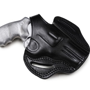 Może przedstawiać: Czarna skórzana kabura do srebrnego rewolweru.