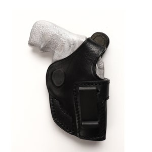 Puede incluir: Una funda de cuero negra con una pistola plateada en su interior. La funda tiene un clip para el cintur&oacute;n.