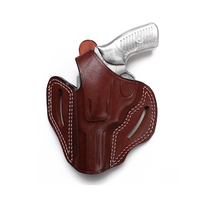 Puede incluir: Una funda de cuero marr&oacute;n con costuras blancas para una pistola plateada.