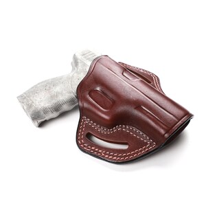 Puede incluir: Una funda de cuero marr&oacute;n para una pistola. La funda tiene un bucle para el cintur&oacute;n y un cierre a presi&oacute;n.