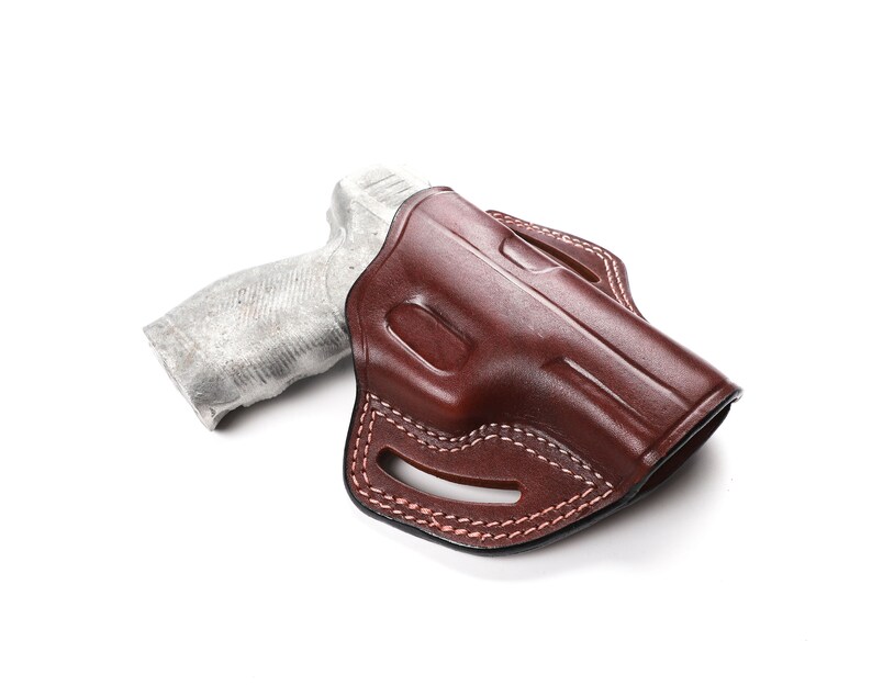 Puede incluir: Una funda de cuero marr&oacute;n para una pistola. La funda tiene un bucle para el cintur&oacute;n y un cierre a presi&oacute;n.