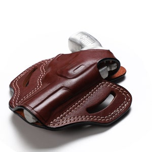 Puede incluir: Una funda de cuero marr&oacute;n con costuras blancas para una pistola peque&ntilde;a.