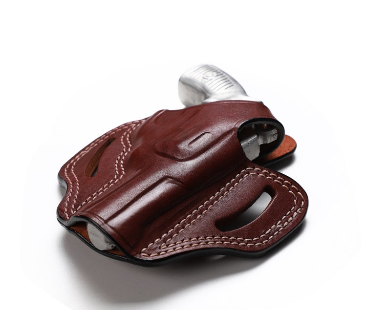 Puede incluir: Una funda de cuero marr&oacute;n con costuras blancas para una pistola peque&ntilde;a.