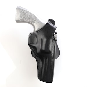 Op de afbeelding: Een zwart leren holster met een zilveren pistool erin.