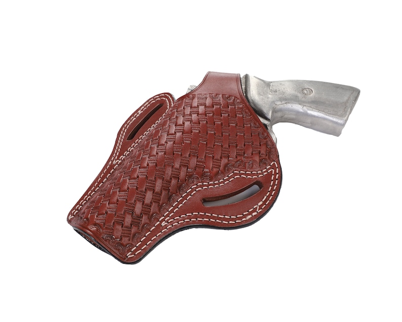 May include: A brown leather holster with a woven pattern and white stitching. The holster is designed to hold a revolver.