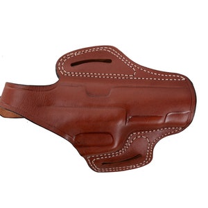 May include: A brown leather holster with white stitching. The holster has a flap that covers the top of the gun.