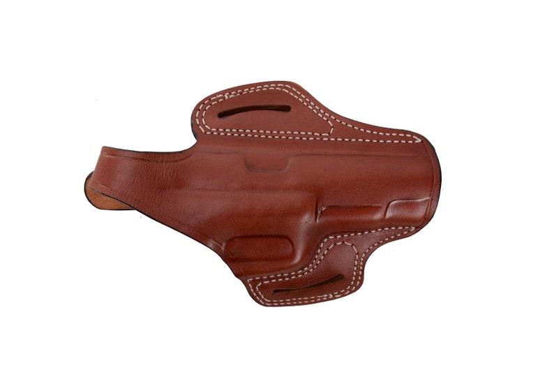 May include: A brown leather holster with white stitching. The holster has a flap that covers the top of the gun.